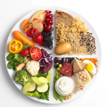 © BMSGPK Fotostudio Mayer mit Hut Darstellung gesunder und nachhaltiger Teller - Hälfte Obst und Gemüse, jeweils ein Viertel Getreide sowie eiweißreiche Lebensmittel